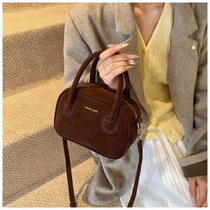Détail du petit sac bandoulière en daim marron avec ferrures dorées et texte de mode