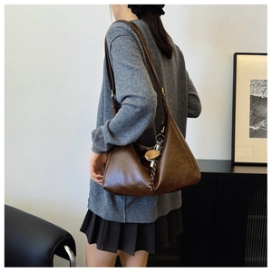 Detail of deep brown faux leather hobo bag with adjustable strap and mushroom charm