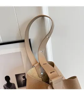 Detail of adjustable wide shoulder strap on a camel leather bucket bag with litchi texture