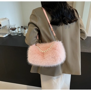 Detail of pink faux fur shoulder bag featuring pearl chain and adjustable leather strap