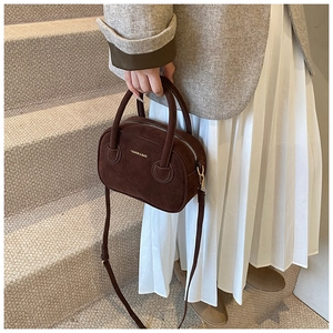 Détail du sac à main en daim marron foncé avec poignées et texte mode sur escalier beige