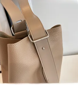Detail of adjustable strap and silver metal buckle on khaki lychee grain leather bucket bag