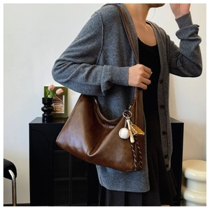 Detail of dark brown hobo bag featuring unique baseball charm and smooth leather texture