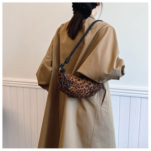 Close-up of leopard print crescent bag with knotted strap on a khaki trench coat