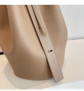 Detail of light tan lychee grain leather bucket bag with wide adjustable shoulder strap