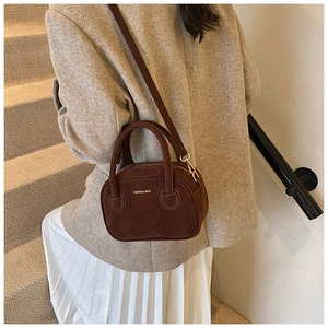 Détail d'un sac à main en daim marron avec lettrage doré et poignée supérieure chic