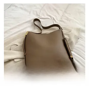 Detail of brown litchi pattern leather tote with gold hardware and side zipper accents