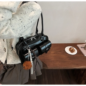 Détail du sac oreiller en cuir noir avec breloque ours en peluche et ruban décoratif