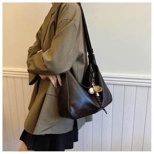 Close-up of deep brown leather hobo bag with a decorative baseball glove charm