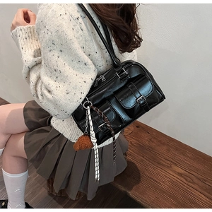 Détail du sac oreiller en cuir PU noir brillant avec poches et pendentif en peluche