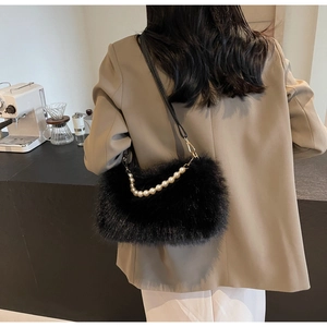 Detailed view of black faux fur bag with pearl chain and thin leather strap on a model