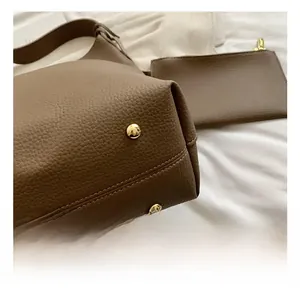 Macro view of brown lychee grain leather tote bag with gold metal feet and clutch detail