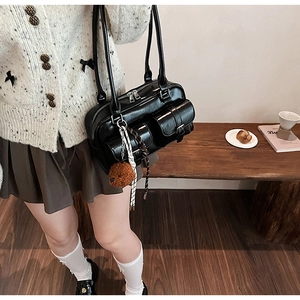Vue de dessus d'un sac à bandoulière en cuir PU noir avec poches et charm ours sur banc