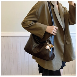 Detail of dark brown large crossbody bag with vintage baseball charms on a model