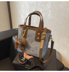 Detail of blue denim mini bucket bag with brown leather trim and cute puppy charm