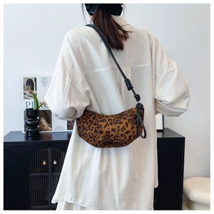 Close-up of leopard print crescent bag with black leather knotted strap shown on person