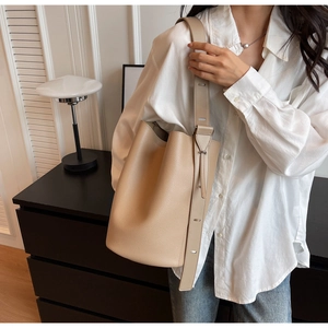 Detail of beige lychee pattern bucket bag with adjustable wide strap on model