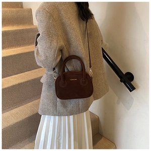 Photo de mode d'un petit sac à main en daim marron foncé avec bandoulière et détails dorés