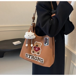 Dettaglio della borsa tote marrone vintage con ricamo a forma di orso e ciondolo