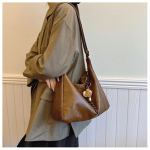 Detailed view of the brown leather shoulder bag with adjustable strap and woven zipper pull