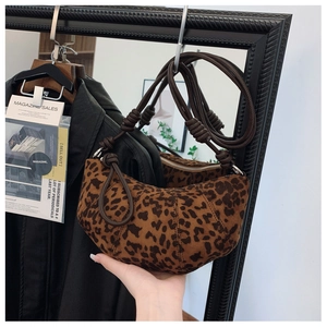 Close-up of leopard print dumpling bag with brown braided knot shoulder strap