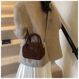 Détail du sac bandoulière en suédine marron avec texte doré et style élégant