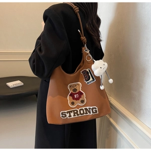Dettaglio della borsa tote marrone vintage con toppe in ciniglia e ciondolo