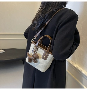 Detail view of cream canvas bucket bag with brown leather trim and puppy charm
