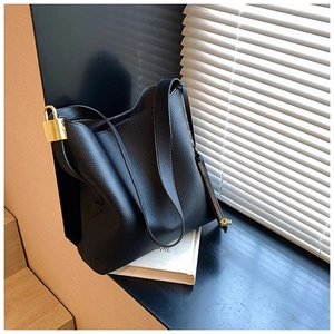 Detailed side view of black pebble leather tote with elegant gold buckle and long zipper tape