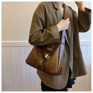 Detail of vintage brown leather hobo bag with zip closure and woven tassel pendant
