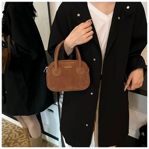 Détail d'un sac bandoulière en daim marron avec lettrage doré et sangle amovible