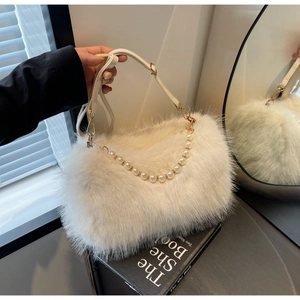 Detail of cream white faux fur bag featuring pearl handle and adjustable gold strap