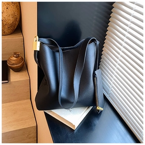 Close-up of black litchi pattern leather tote bag with golden lock and inner pouch