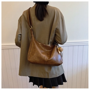 Detailed view of brown PU leather crescent hobo bag with a decorative dice pendant