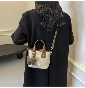 Detail of canvas bucket bag with brown leather trim shown on model in black coat