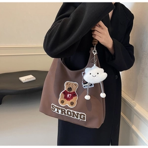 Dettaglio borsa tote marrone con ricamo a forma di orso e ciondolo a nuvola bianca