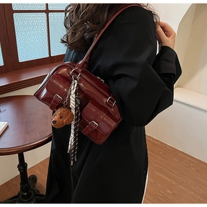 Gros plan du sac bandoulière vintage rouge foncé avec pendentif ours et foulard