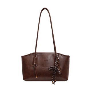 Deep brown leather tote bag with vintage matte finish and woven bow charm on white background