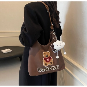 Dettaglio borsa tote in pelle marrone con ricamo orsetto e ciondolo a forma di nuvola