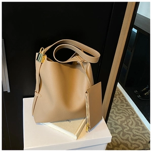 Close-up of beige lychee textured bucket bag set with gold lock and wide shoulder strap