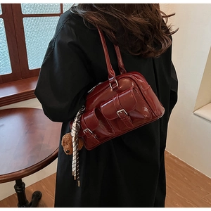Detail of burgundy glossy leather underarm bag with metal buckles and scarf accessory