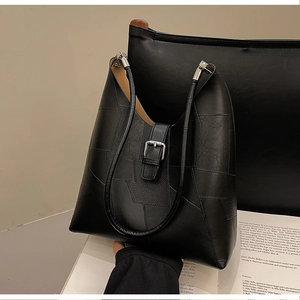 Detail of black patchwork leather shoulder bag featuring silver buckle and sleek texture