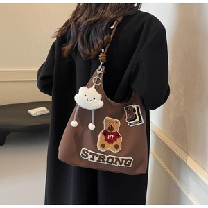 Dettaglio borsa tote in tela marrone con ricamo orso e ciondolo nuvola in peluche