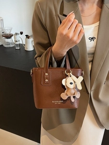 Braune Leder-Henkeltasche im Bucket-Stil mit Tieranhänger und Marken-Schriftzug