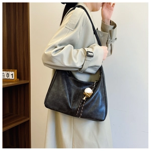 Detail view of a retro dark grey crescent bag with a decorative baseball glove pendant