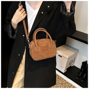 Détail d'un mini sac à main en daim marron avec lettrage doré et bandoulière amovible