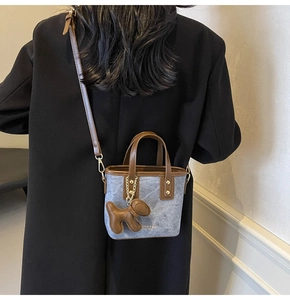 Blue denim mini tote bag with brown leather accents and cute puppy charm on back view