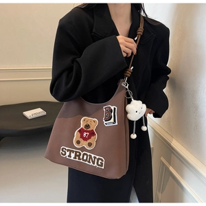 Dettaglio borsa tote marrone vintage con ricamo a orsetto e ciondolo a nuvola bianca