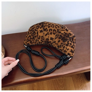 Detail of leopard print suede croissant bag with black rope strap on wooden bench