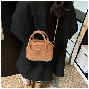 Gros plan d'un mini sac en daim marron avec logo doré et attaches de bandoulière